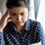 asian woman reading letter looking frustrated