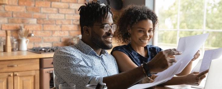 black couple smiling, looking at paper documents
