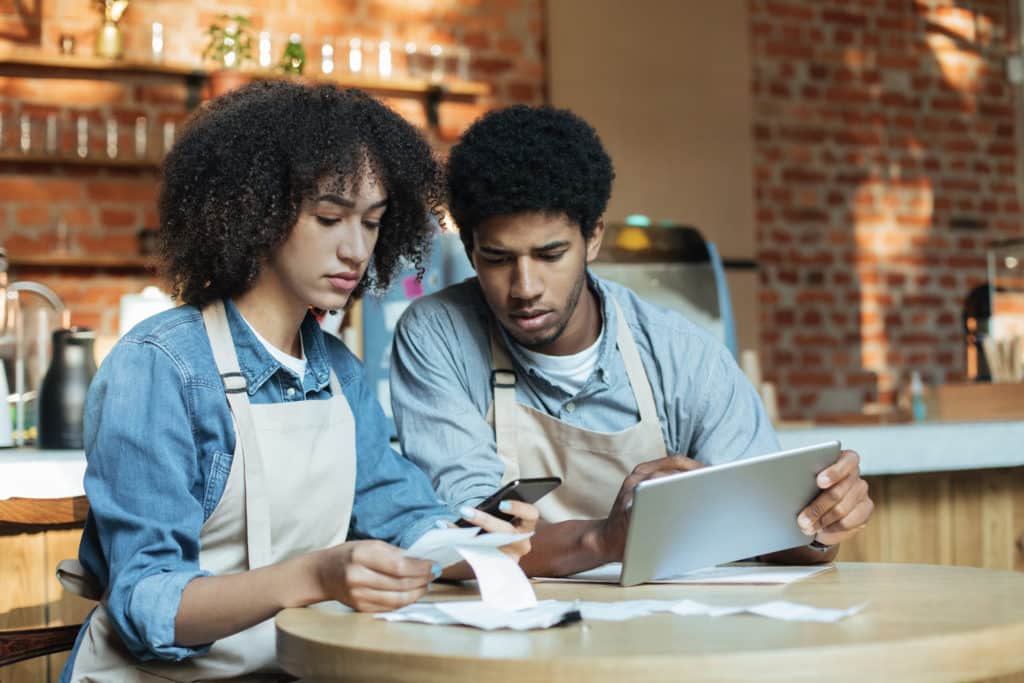 black woman and black man who work at restaurant looking at smart phone