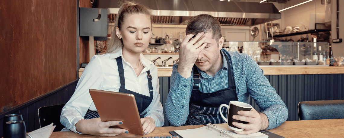 two restaurant business owners looking at tablet upset about merchant cash advance default