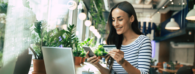 white woman holding credit card looking at laptop